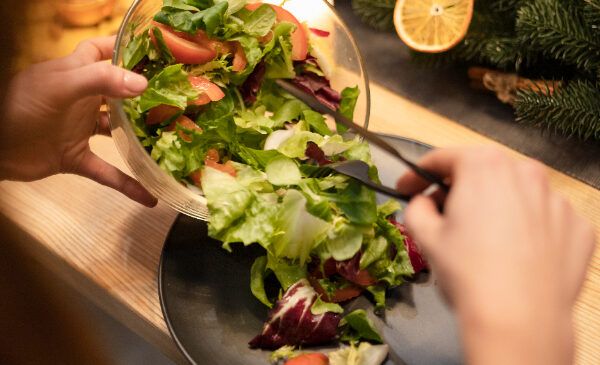 Mujer sirviendo ensalada en la cena navideña