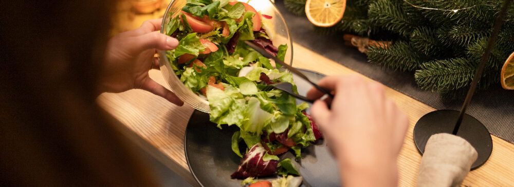 Mujer sirviendo ensalada en la cena navideña